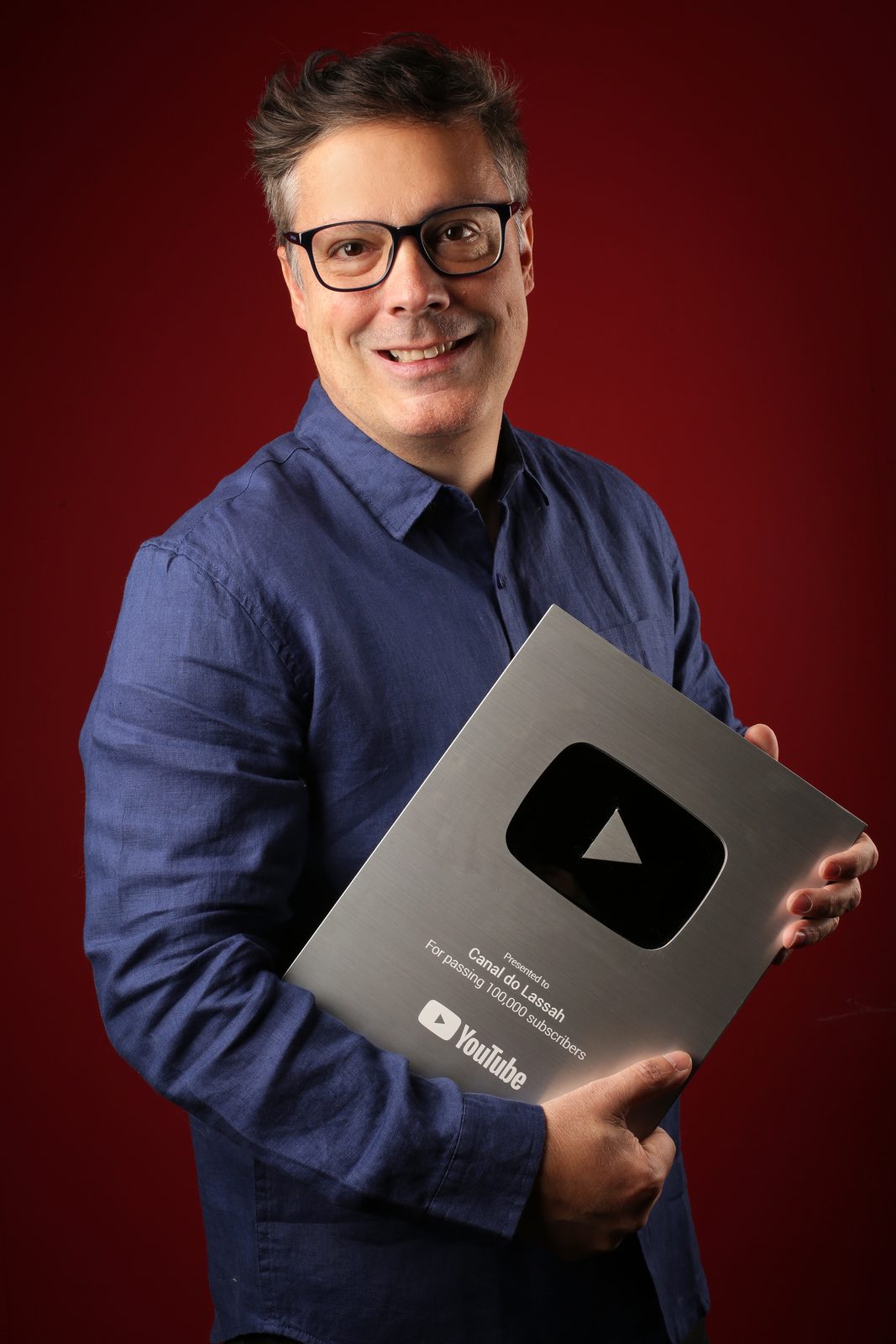 Eduardo Lassah, ator, segurando a placa de 100 mil inscritos do YouTube