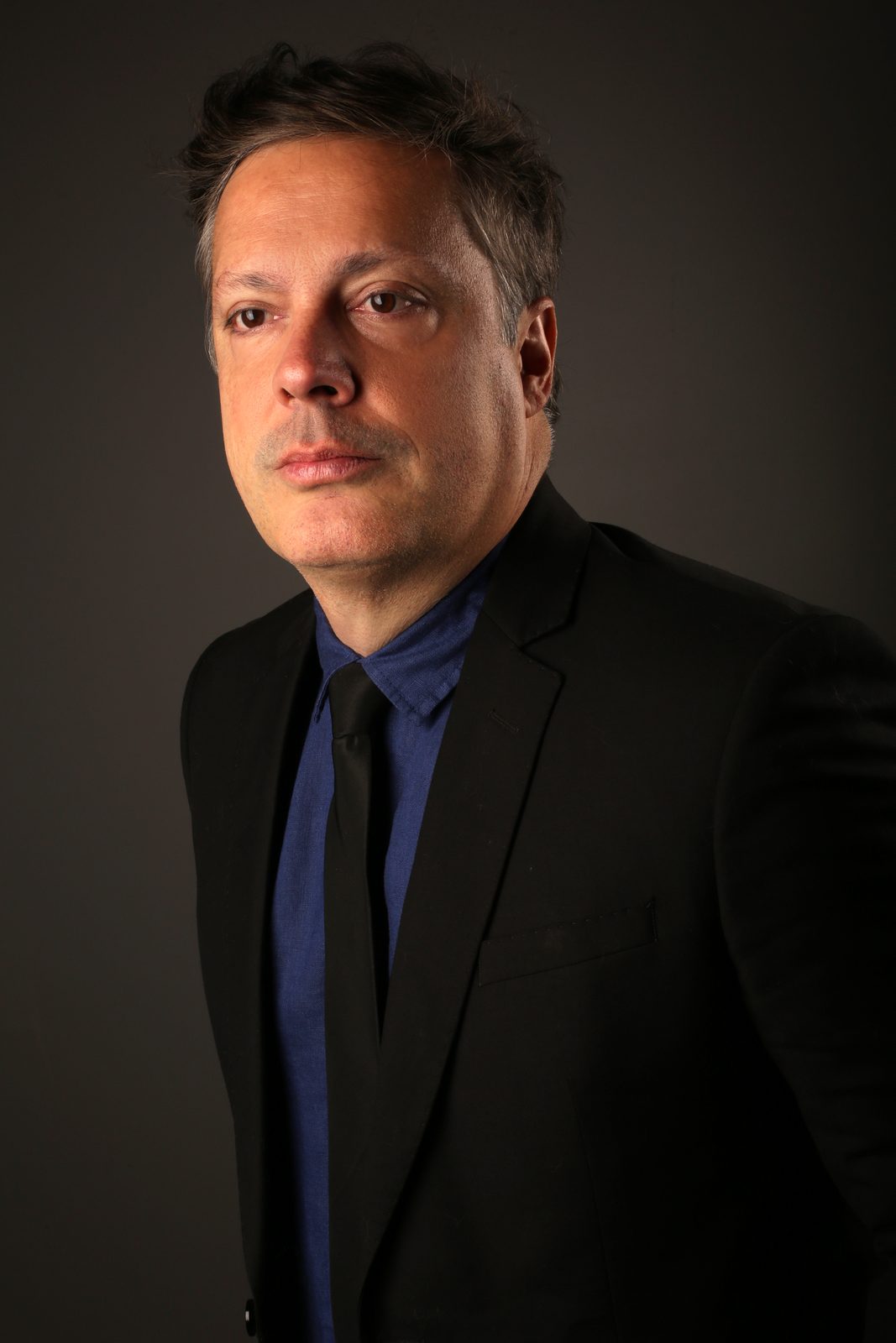 Eduardo Lassah, ator, em retrato dramático de terno preto